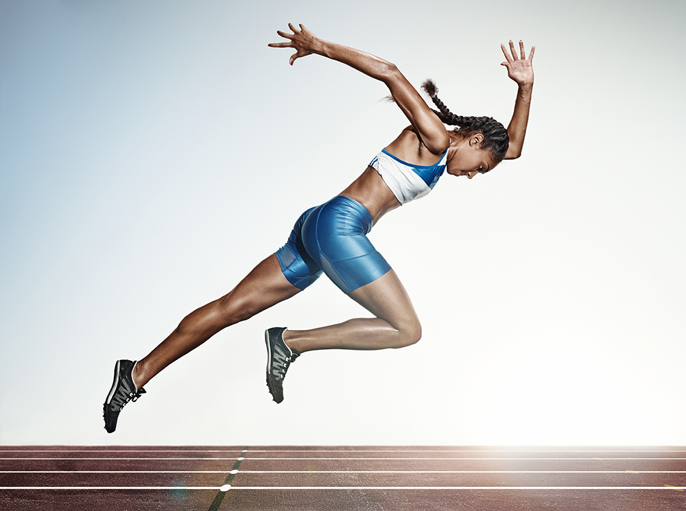 Woman in running form about to begin sprinting down an outdoor track.