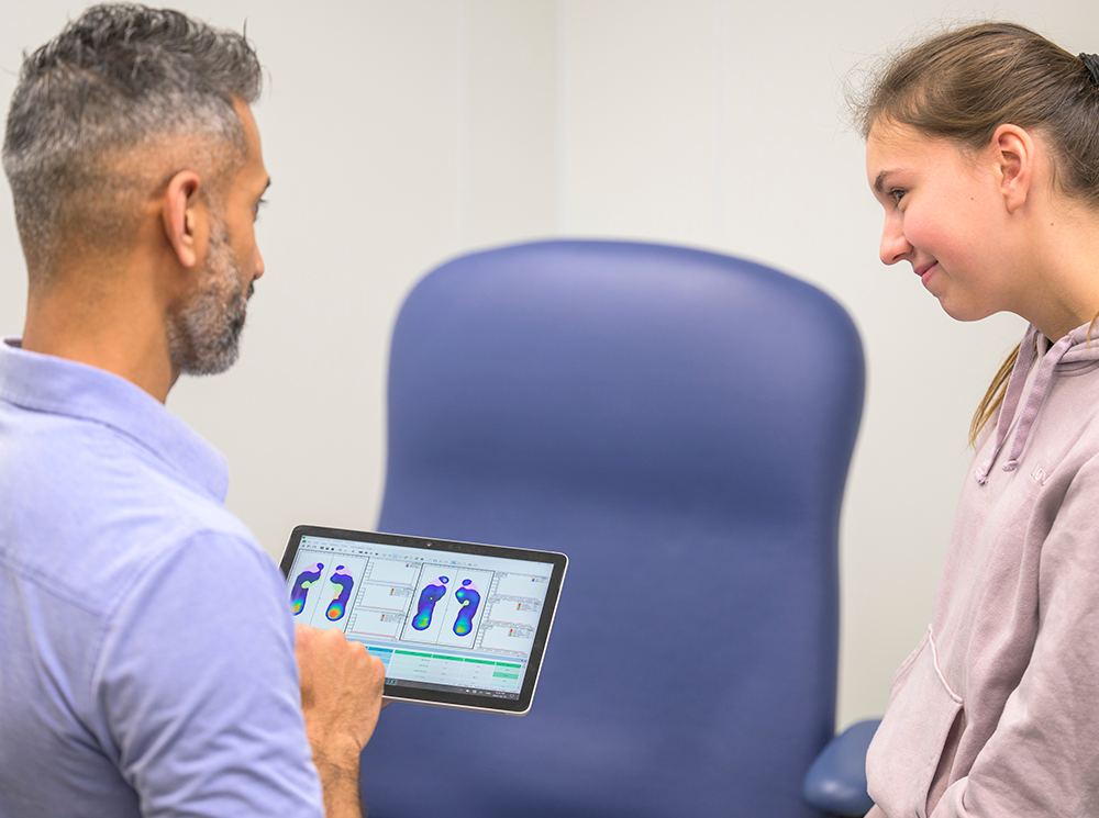 Podiatrist examining plantar pressure data with a client. Podiatrist examining plantar pressure data with a client.