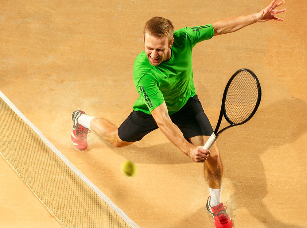 Tennis player swinging tennis racket at a tennis ball.