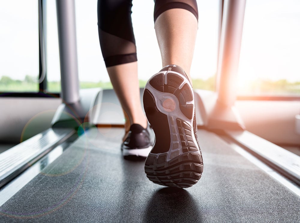 Person walking on a treadmill in running shoes. Person walking on a treadmill in running shoes.