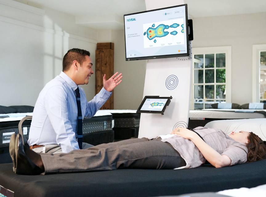 Sales associate using REVEAL Educate software to show an individual's pressure map.