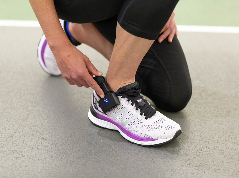 Runner turning on a pair of XSENSOR's Intelligent Insoles in their shoes.