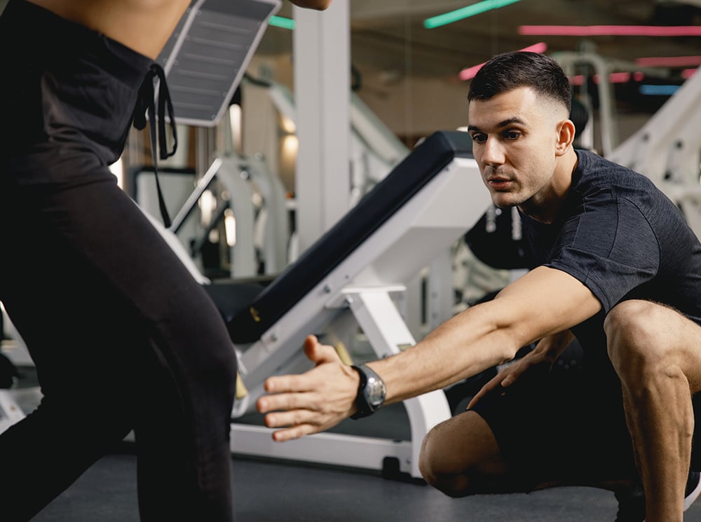 Athletic trainer helping an athlete with an exercise.