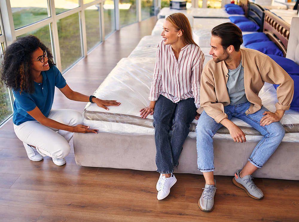 A salesperson helping a couple test a mattress.