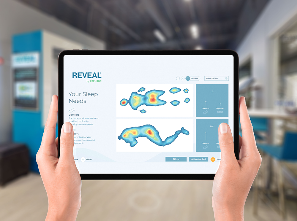 A person holding a tablet with REVEAL by XSENSOR's Educate software showing two pressure maps.