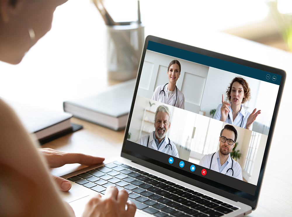 An individual interacting with a team of doctors on a computer.