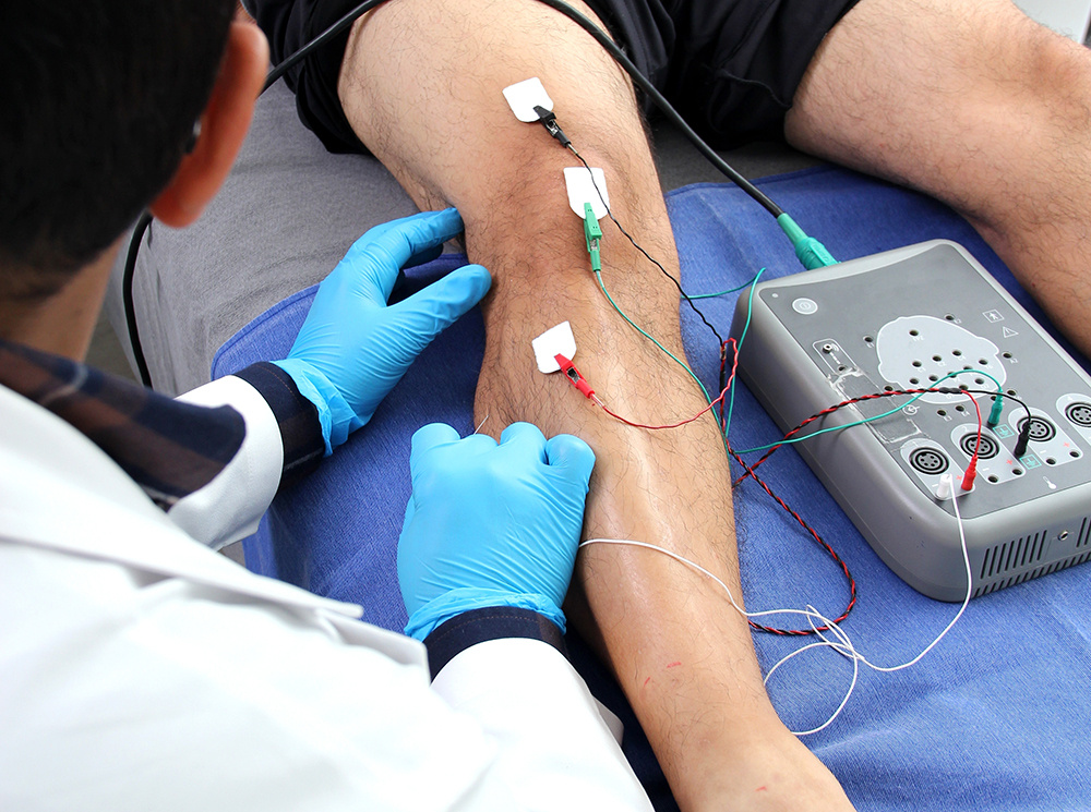 A Clinician using an sEMG on an individual's lower legs.