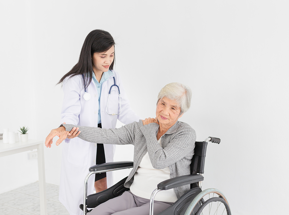 Therapist aiding a wheelchair user with should exercises.