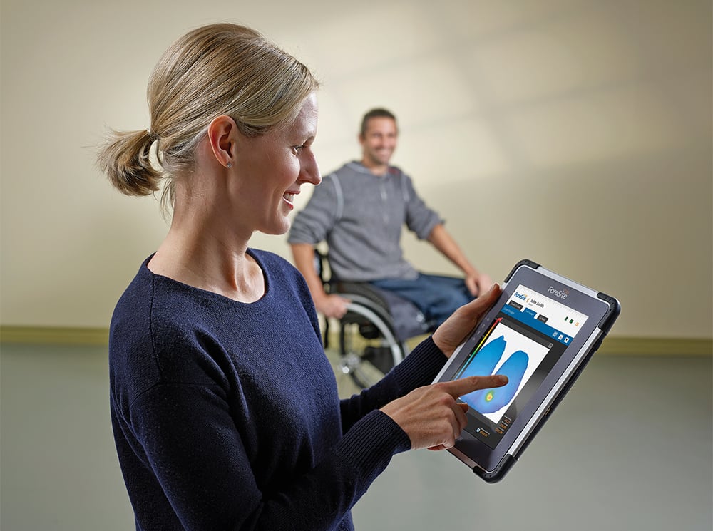 A female clinician looks at the pressure image from a wheelchair user using the ForeSite SS Wheelchair Seating system.