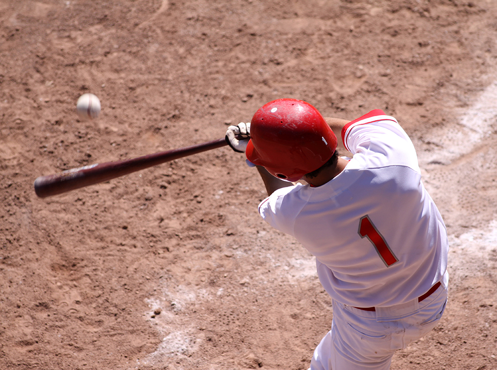 Baseball player swinging a bat at a baseball.