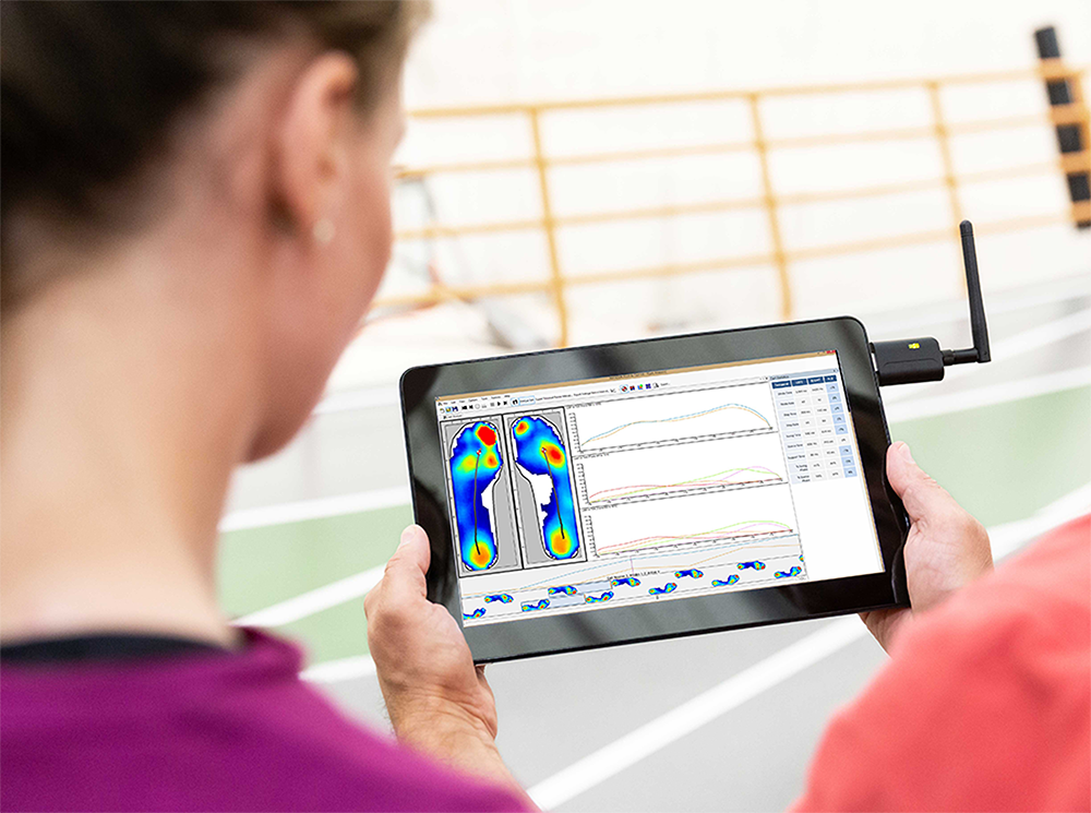 Female athlete reviewing plantar pressure data with her coach on a tablet.