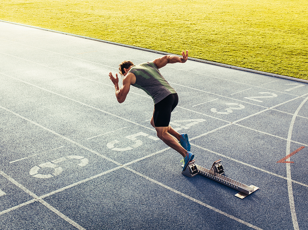 Athlete sprinting off of a starting block.